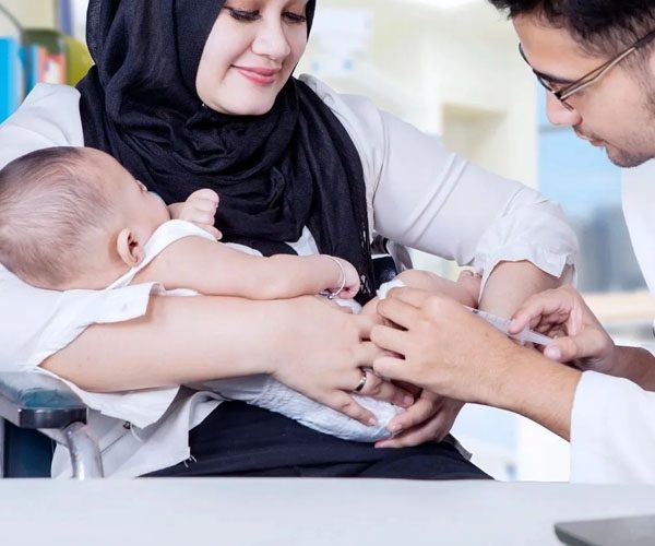 A woman holding a baby while another person holds it.